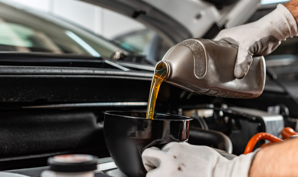 partial view of mechanic pouring motor oil at car engine